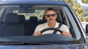 Driver wearing ThinOptics sunglasses while operating a vehicle in bright daylight conditions.