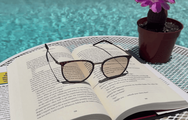 ThinOptics Prescription Glasses with progressive lenses resting on a book by the pool.