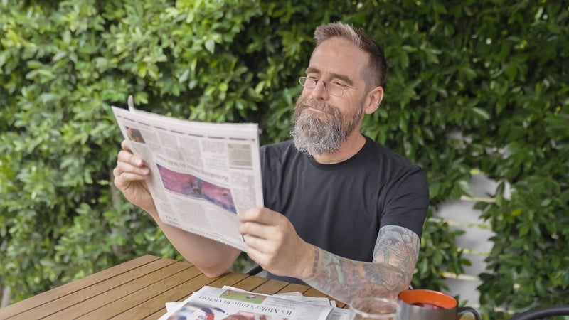 Man wearing ThinOptics Readers and reading a newspaper.