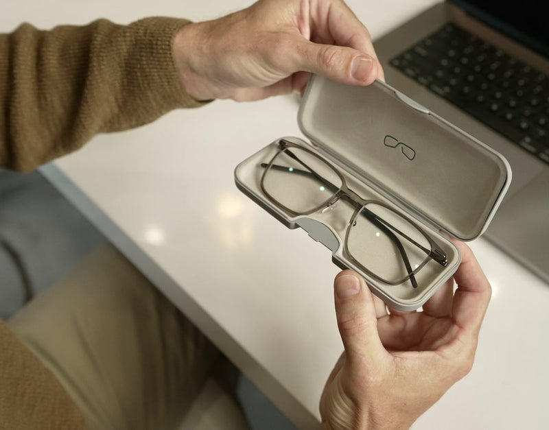 Man holding a pair of ThinOptics Rx Prescription Glasses in their case in front of a laptop.