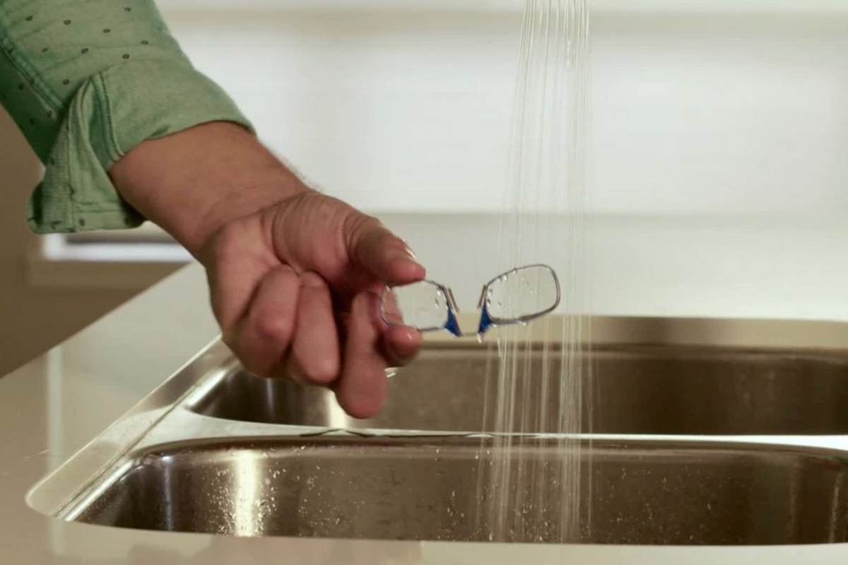 Man washing a pair of ThinOptics Readers in the sink.
