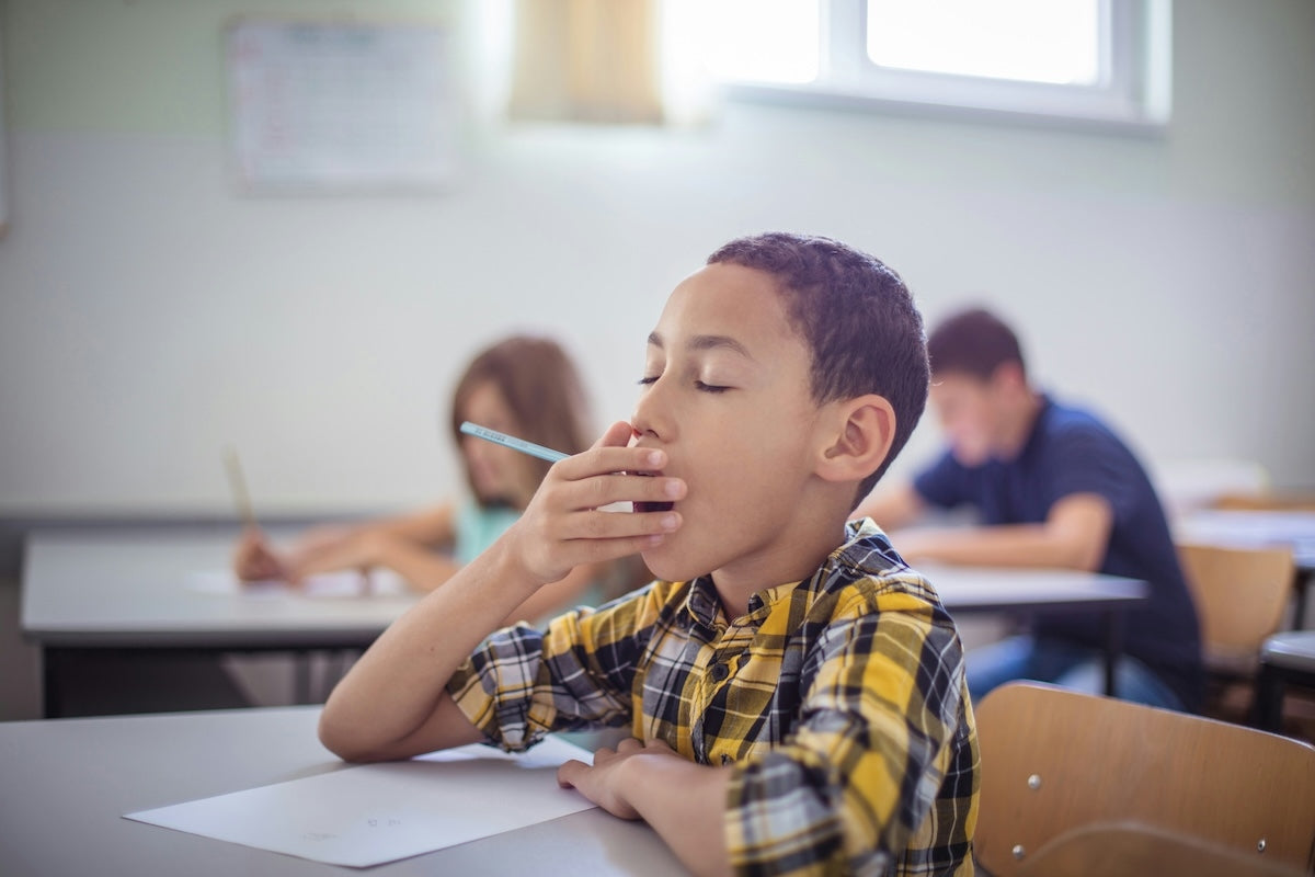 Kid in classroom yawning.