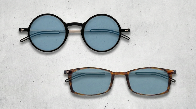 Two pairs of ThinOptics reading sunglasses displayed on a light textured surface.