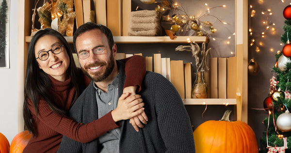 man and woman wearing various ThinOptics products in a festive holiday setting in front of a decorated bookshelf