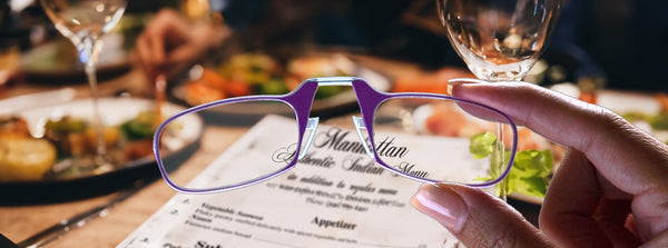 Closeup of ThinOptics Readers held in hand by their ultra slim frames at a restaurant