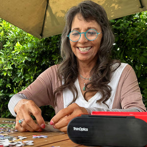 ThinOptics reading glasses and a sleek black case: minimalist design with thin and round lenses. The compact, brushed metal case offers a modern, portable solution for individuals needing reading glasses.