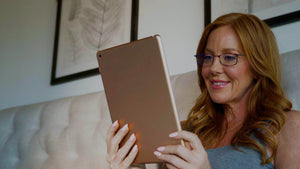 Woman wearing blue light blocking reading glasses while using her tablet