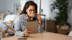 Woman wearing ThinOptics Brooklyn Full Frame Reading Glasses, Blue Light Blockers with ThinOptics Milano Case looking at tablet