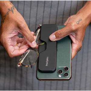 ThinOptics full frame Connect Reading Glasses being pulled from their magnetic case on a smart phone by a woman's hands