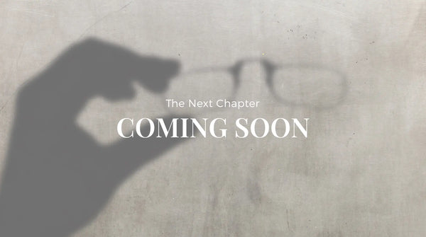 Shadow of a hand holding a pair of glasses cast on a concrete surface with the text Coming Soon overlaid