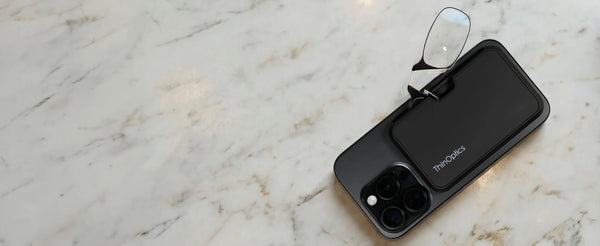 ThinOptics ultra-slim reading glasses stored in MagSafe phone case on marble surface