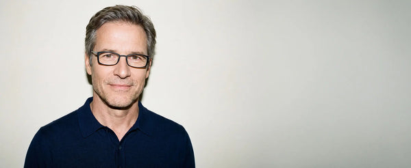 Man wearing ThinOptics black Brooklyn rectangle glasses in a navy polo shirt against a neutral background