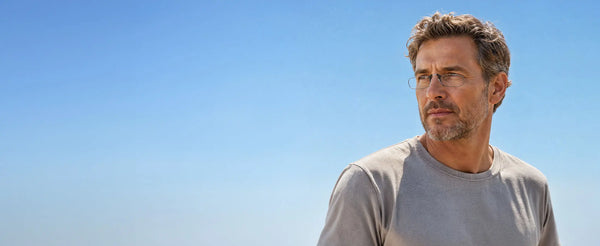 Man wearing ThinOptics thin rectangular glasses gazing into the distance against a bright clear blue sky