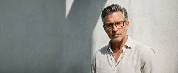 Man wearing ThinOptics Brooklyn tortoise rectangle glasses standing against a concrete wall in natural sunlight