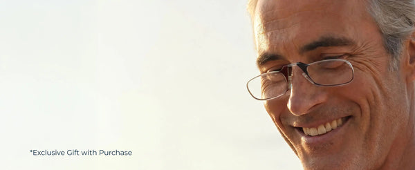 Close-up of a smiling man wearing ThinOptics Moment black armless reading glasses in warm natural light