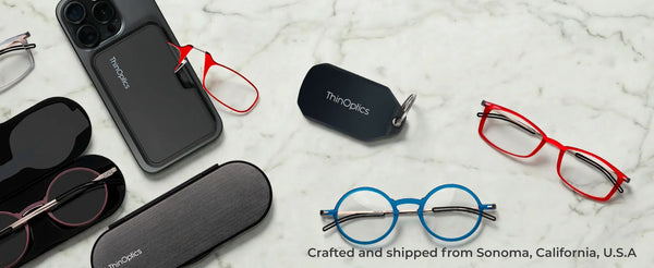 ThinOptics reading glasses and slim phone case holder displayed on marble surface with colorful reader frames and accessories