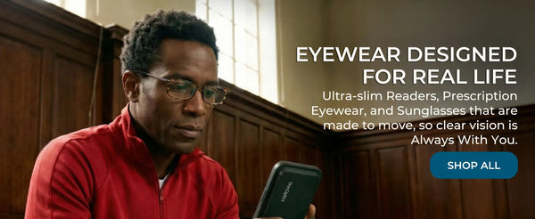 Man wearing ThinOptics reading glasses looking at smartphone with slim phone-mounted case in indoor setting