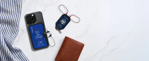 ThinOptics USA 250th anniversary limited edition phone case with We the People design and keychain case with armless readers on a marble surface with a leather wallet