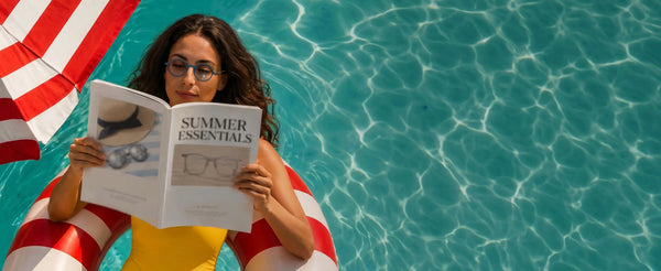 Woman wearing ThinOptics blue round Manhattan prescription glasses reading a Summer Essentials magazine on a pool float