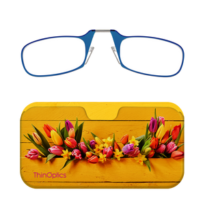 Blue ThinOptics reading glasses rest on a vibrant yellow floral glasses case. The case showcases a bouquet of tulips and daffodils against a rustic wooden background. 
