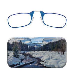Blue ThinOptics reading glasses folded atop a slim case showcasing a snowy forest scene. 
