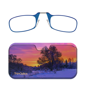 Blue ThinOptics reading glasses folded in their matching case featuring a sunset over a snowy landscape. 
