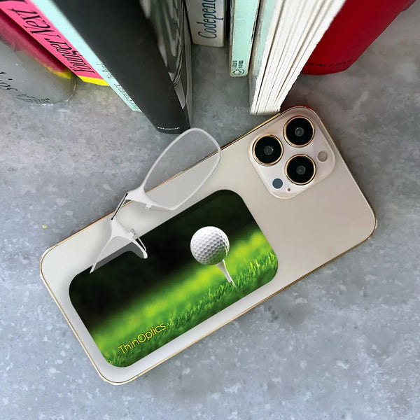 Clear ThinOptics Readers peeking out of a Tee Off Universal Pod attached to a phone being held up by a hand