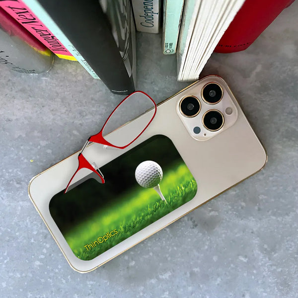 Red ThinOptics Readers peeking out of a Tee Off Universal Pod attached to a phone being held up by a hand