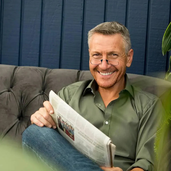 Man wearing black ThinOptics Readers while reading a newspaper