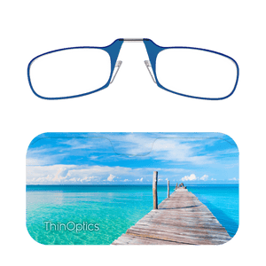 ThinOptics blue reading glasses folded atop a slim carrying case featuring a wooden pier extending over turquoise ocean water. 
