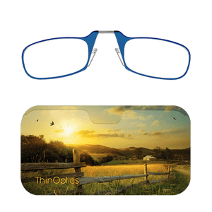 Blue ThinOptics reading glasses folded atop a slim case featuring a sunset over a fence line and grassy field. 
